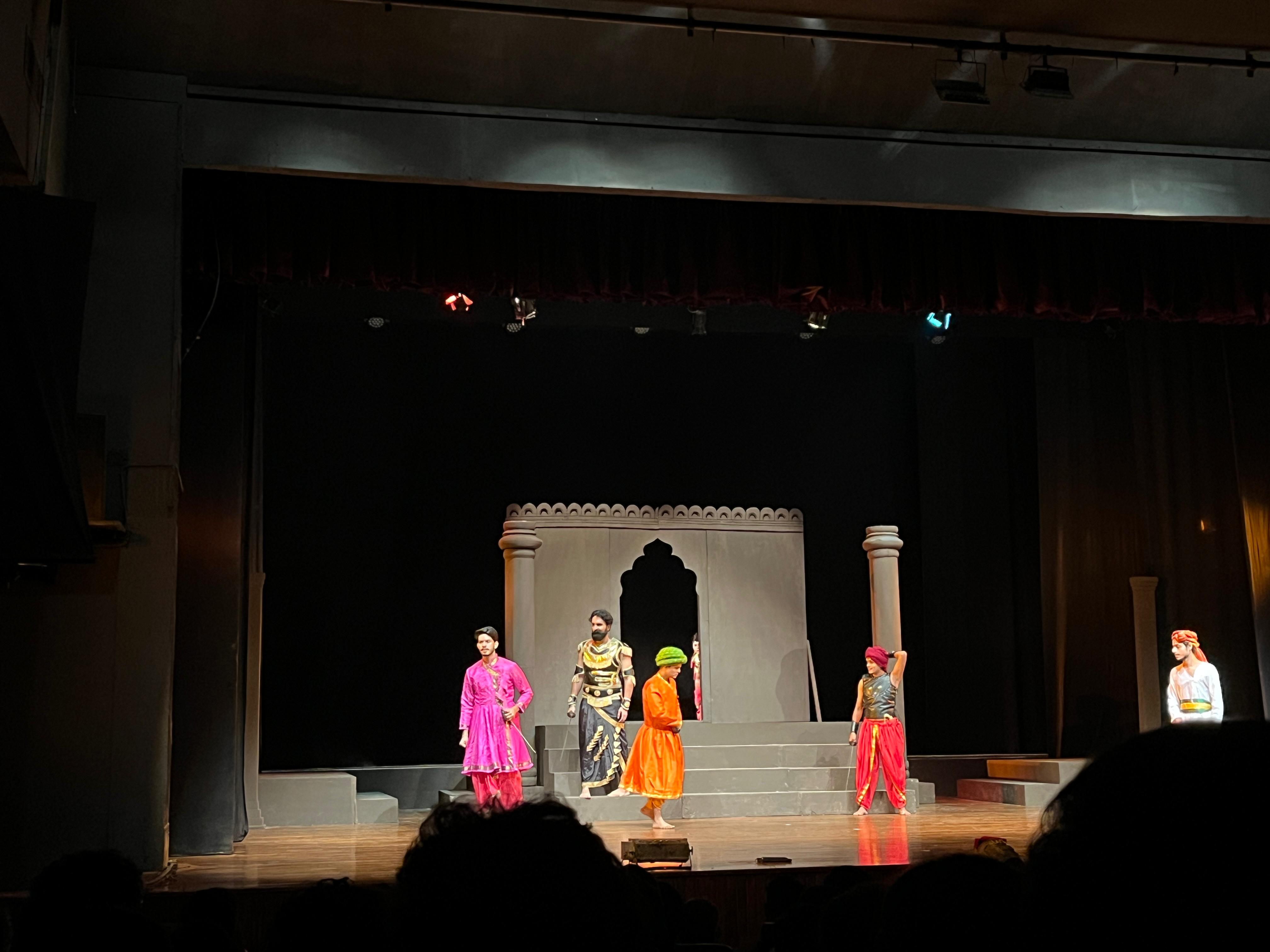 Costumed performers in front of palace scenery