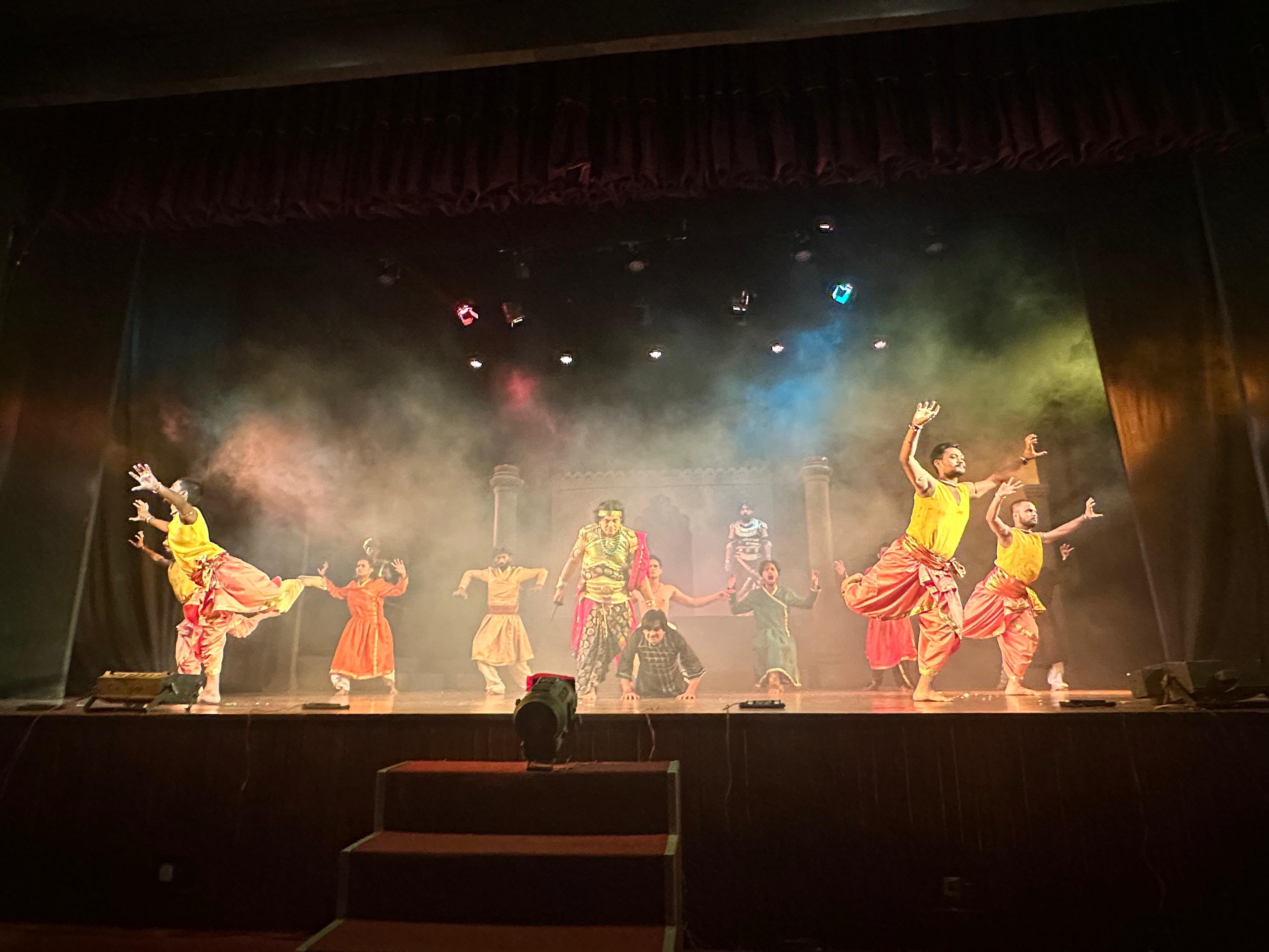 Ensemble dancers performing across a smoke-filled stage