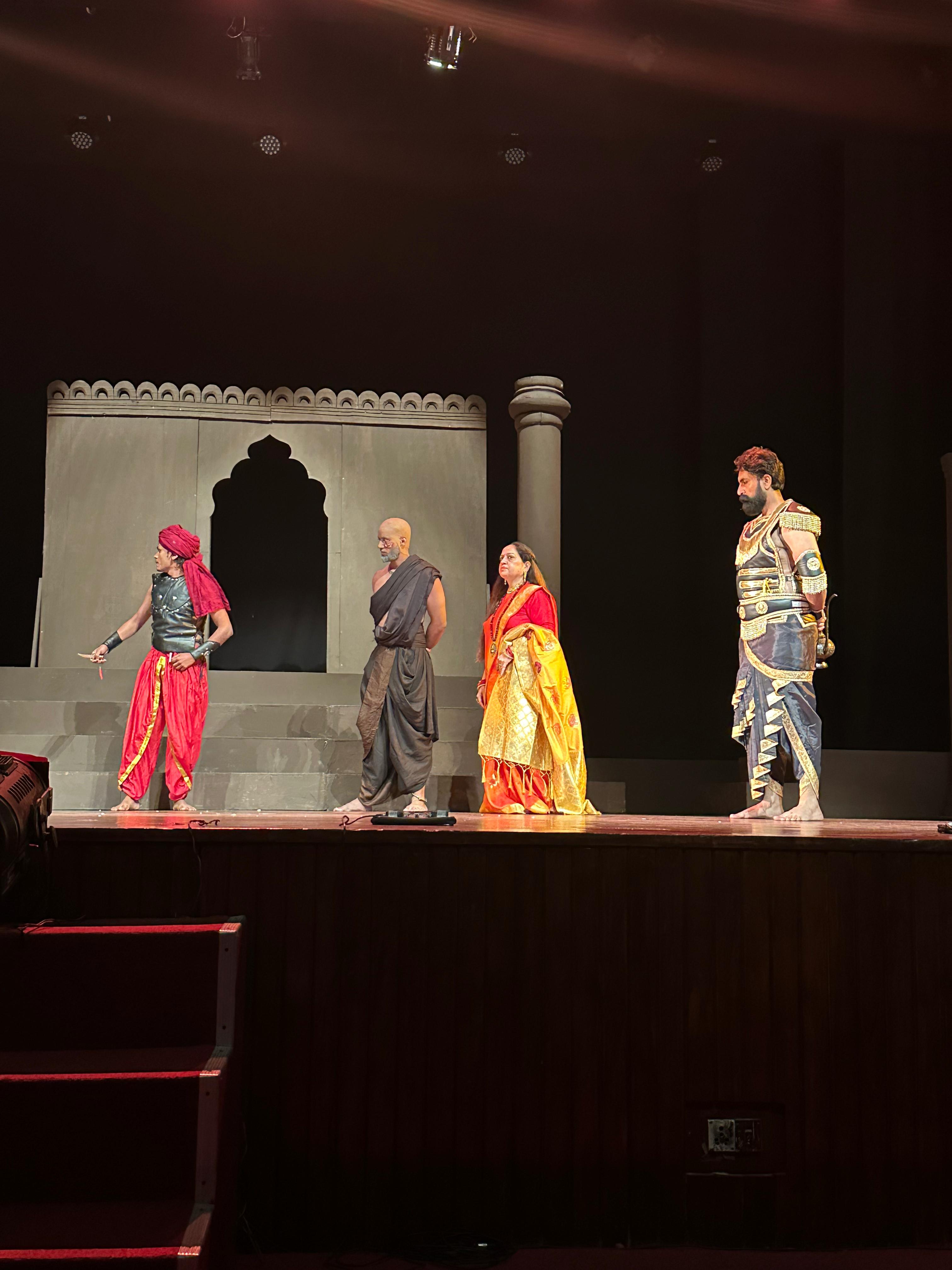Four costumed actors in a palace scene
