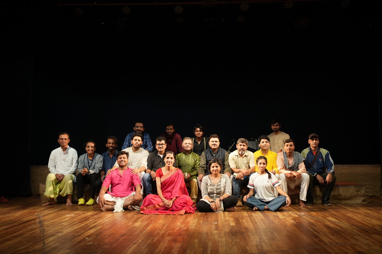 The theatre team posing together on a wooden stage