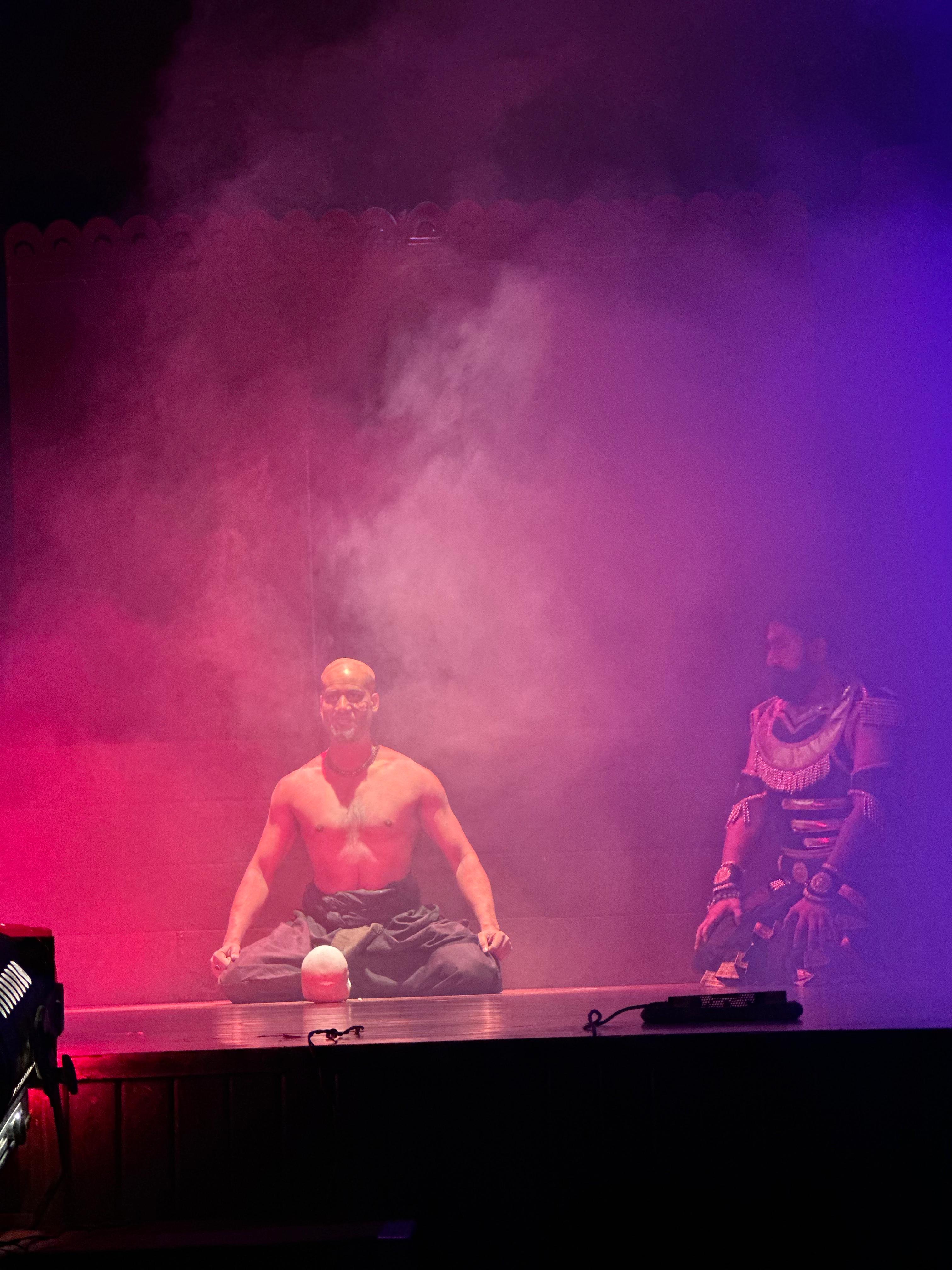 Two actors surrounded by pink and purple stage smoke