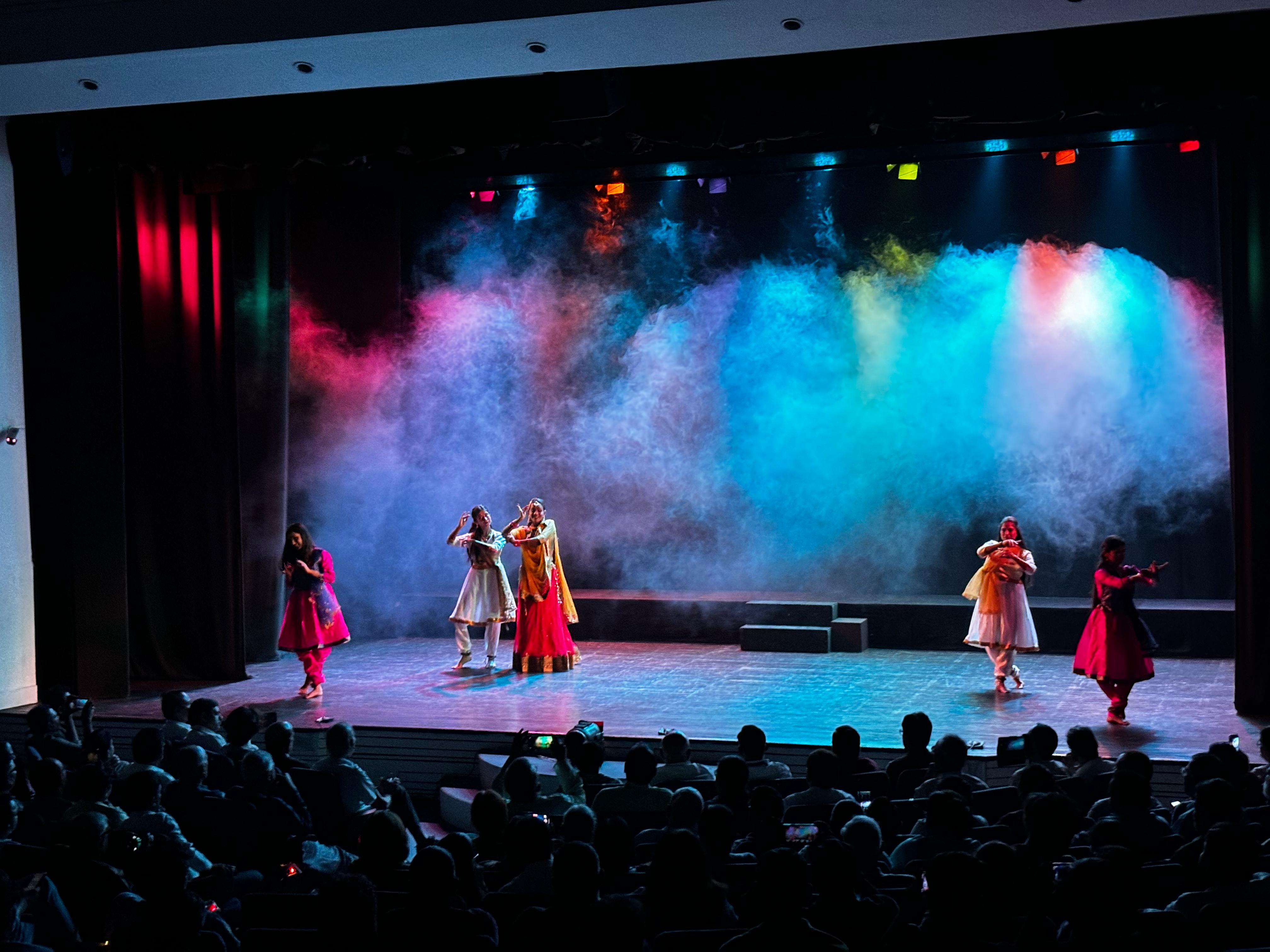 Dancers on stage beneath blue and pink lights