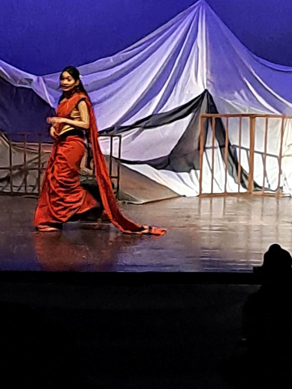 Performer in a red sari crossing the stage