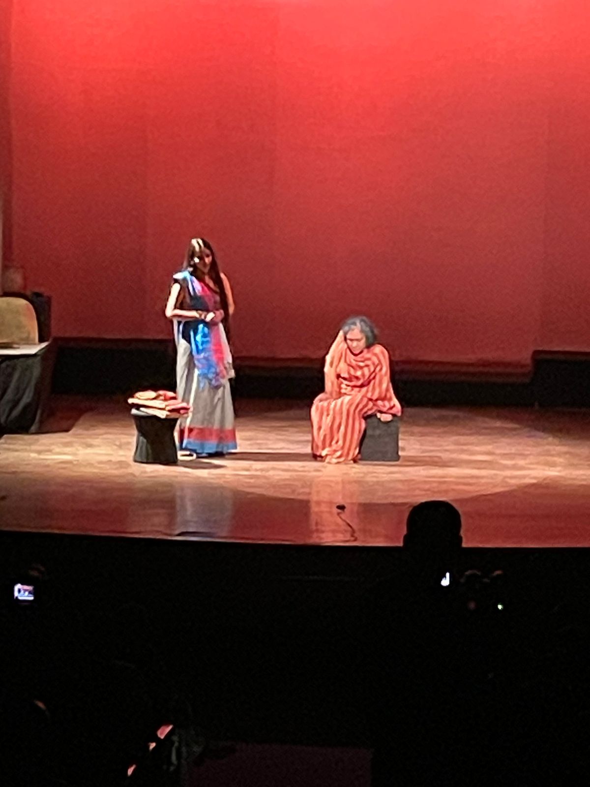 Two performers in a scene against a red backdrop