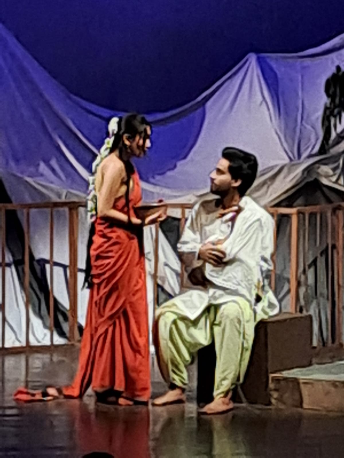Two actors conversing beside a stage railing