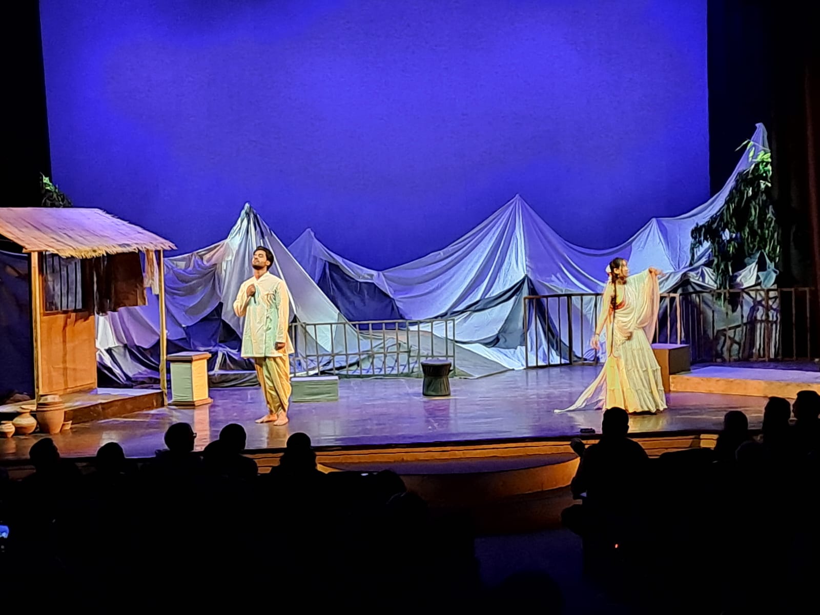 Two performers standing apart on a mountain-inspired stage set