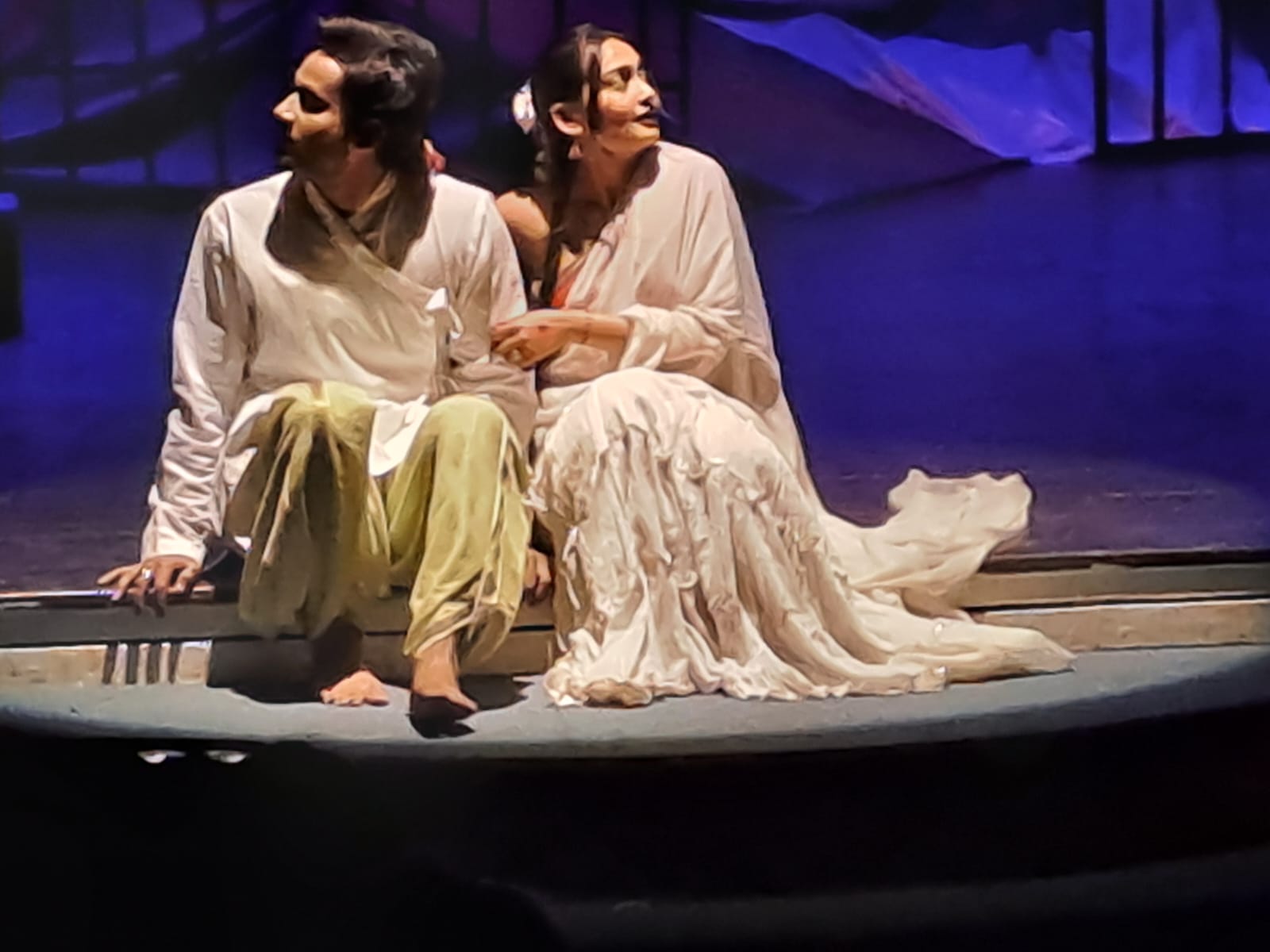 Close view of two performers seated at the edge of the stage
