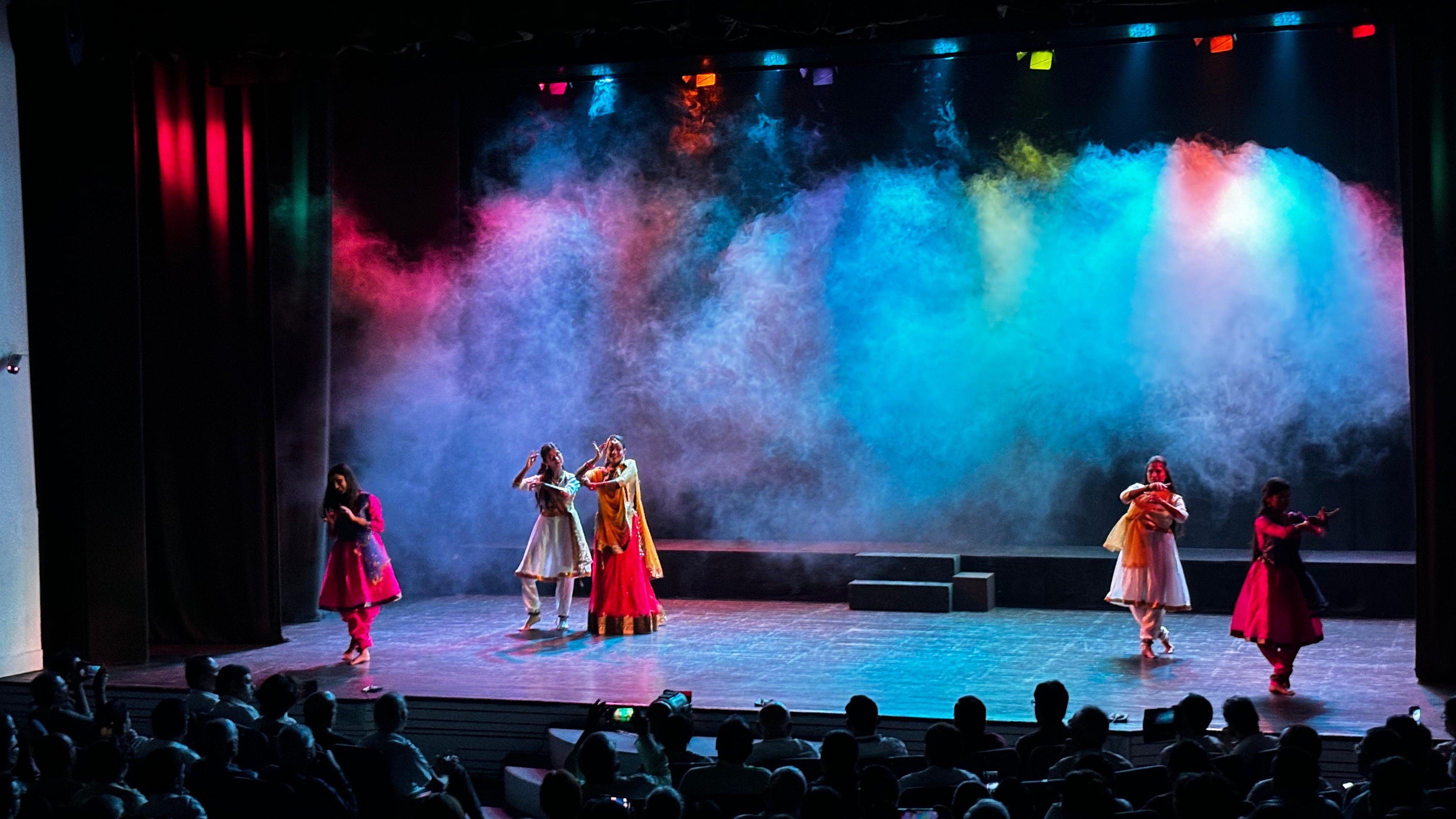 Performers on stage beneath colourful blue and pink lights